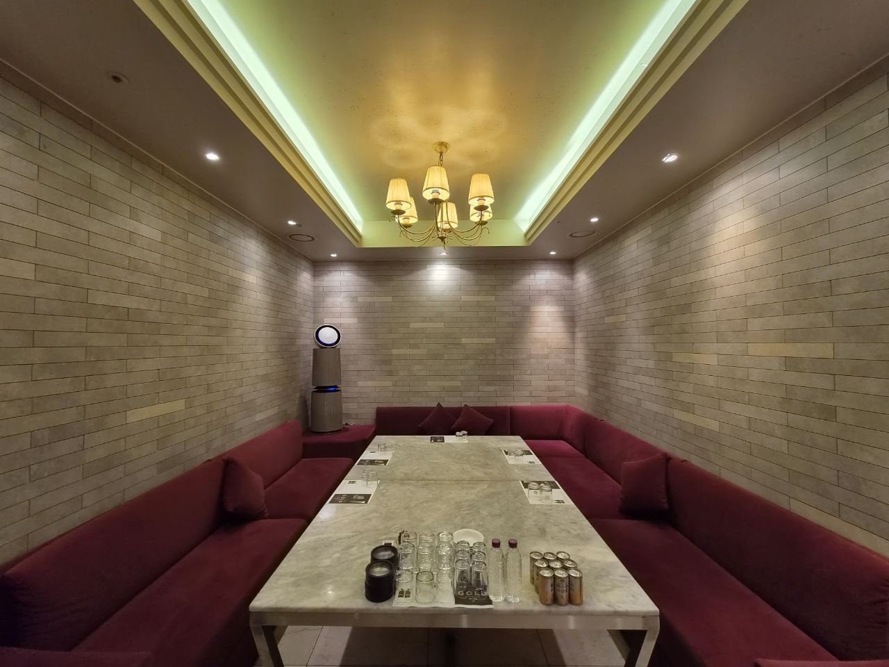 강남알파벳 버건디 벨벳 룸 — 와인빛 벨벳 소파와 브릭 텍스처 월